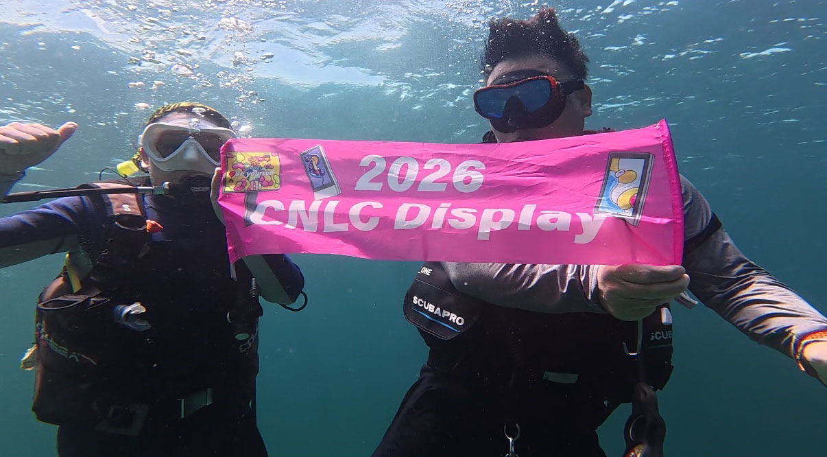 CNLC team holding the company flag underwater in Semporna, Malaysia, symbolizing the company's global vision and commitment to outdoor digital signage innovation.
